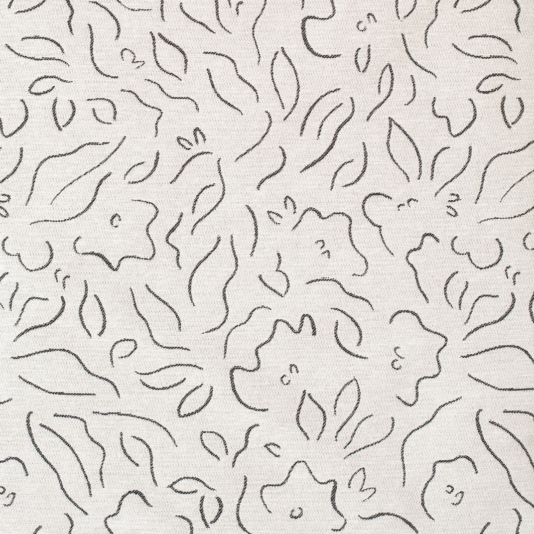 Detail of fabric in a minimalist floral print in charcoal on a cream field.