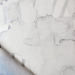 Draped fabric yardage in an abstract watercolor print in shades of gray on a white field.