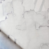 Draped fabric yardage in an abstract watercolor print in shades of gray on a white field.