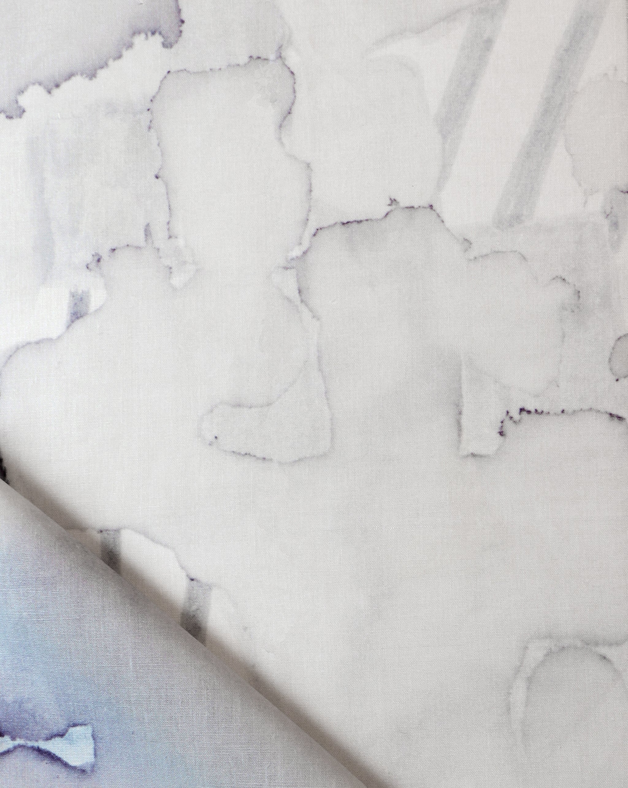 Draped fabric yardage in an abstract watercolor print in shades of gray on a white field.