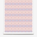 Partially unrolled wallpaper yardage in a gridded paint splatter print in shades of pink, blue, tan and white.