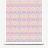 Partially unrolled wallpaper yardage in a gridded paint splatter print in shades of pink, blue, tan and white.