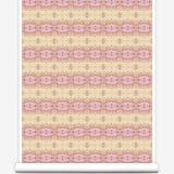 Partially unrolled wallpaper yardage in a gridded paint splatter print in shades of pink, orange, yellow and white.