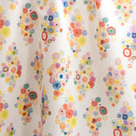 Draped fabric yardage in a painterly floral print in multicolor pastels on a white field.