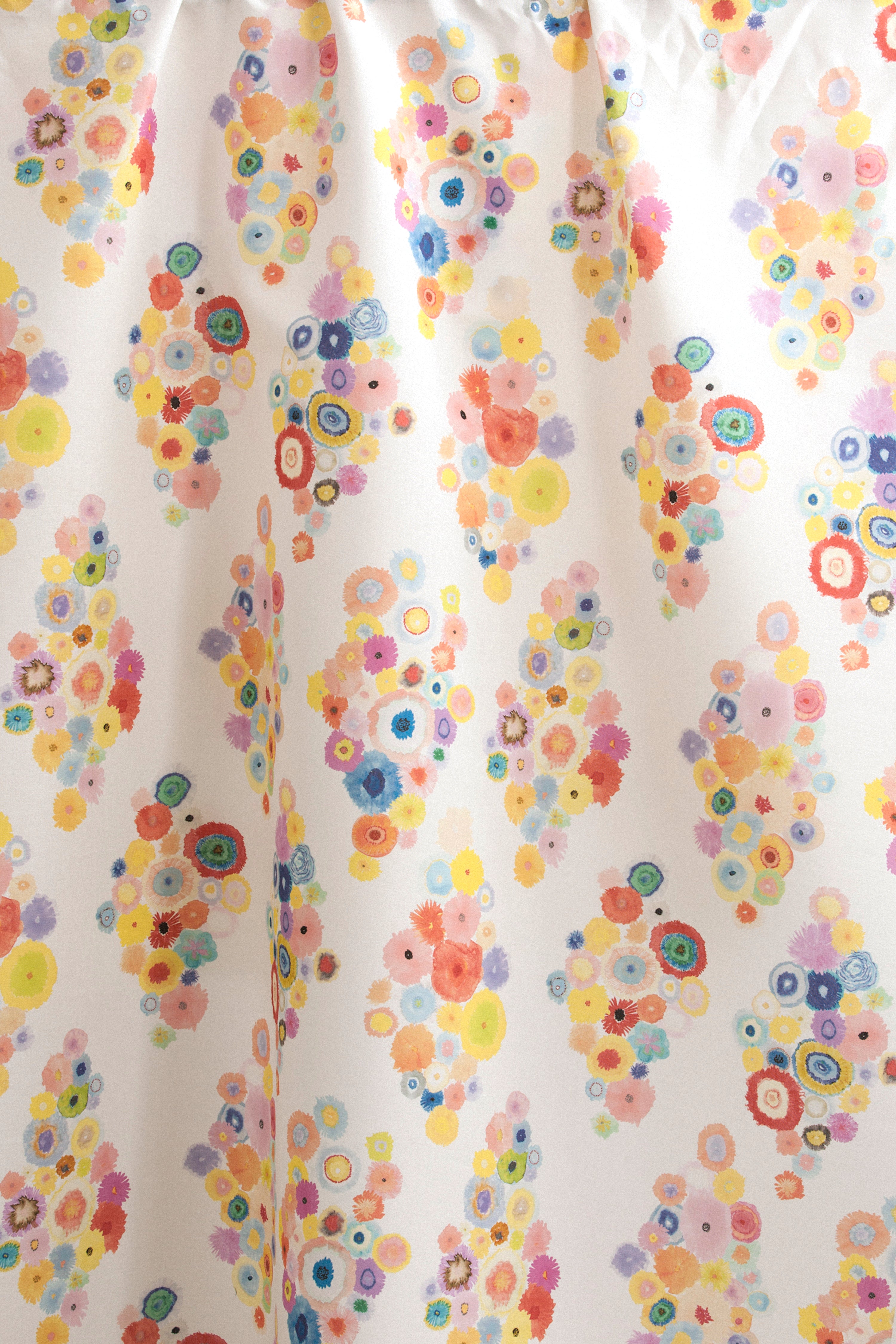 Draped fabric yardage in a painterly floral print in multicolor pastels on a white field.