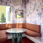 A modernist dining room with an open window and walls papered in a painterly herringbone print in blue, pink and orange.