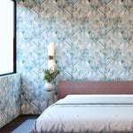 A modernist bedroom with a large window and walls papered in a painterly herringbone print in shades of blue, green and brown.