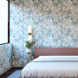 A modernist bedroom with a large window and walls papered in a painterly herringbone print in shades of blue, green and brown.