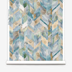 Partially unrolled wallpaper yardage in a painterly herringbone print in shades of blue, green and brown.