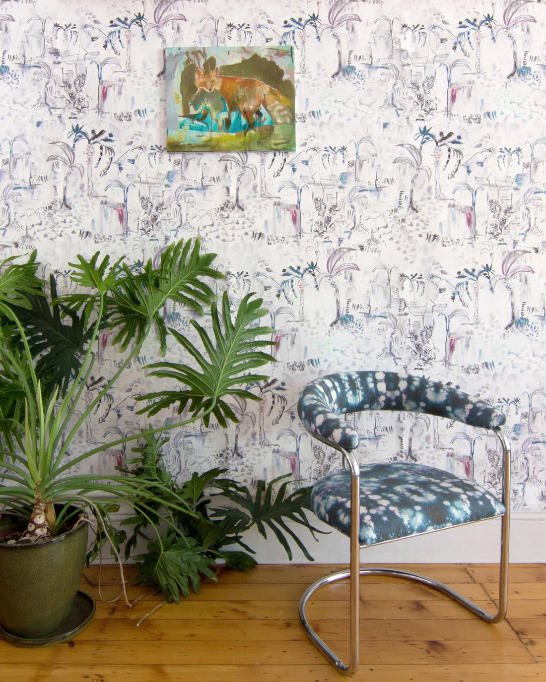 Modernist living tableau with a large plant and a statement wall papered in a painterly botanical print.