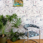 Modernist living tableau with a large plant and a statement wall papered in a painterly botanical print.