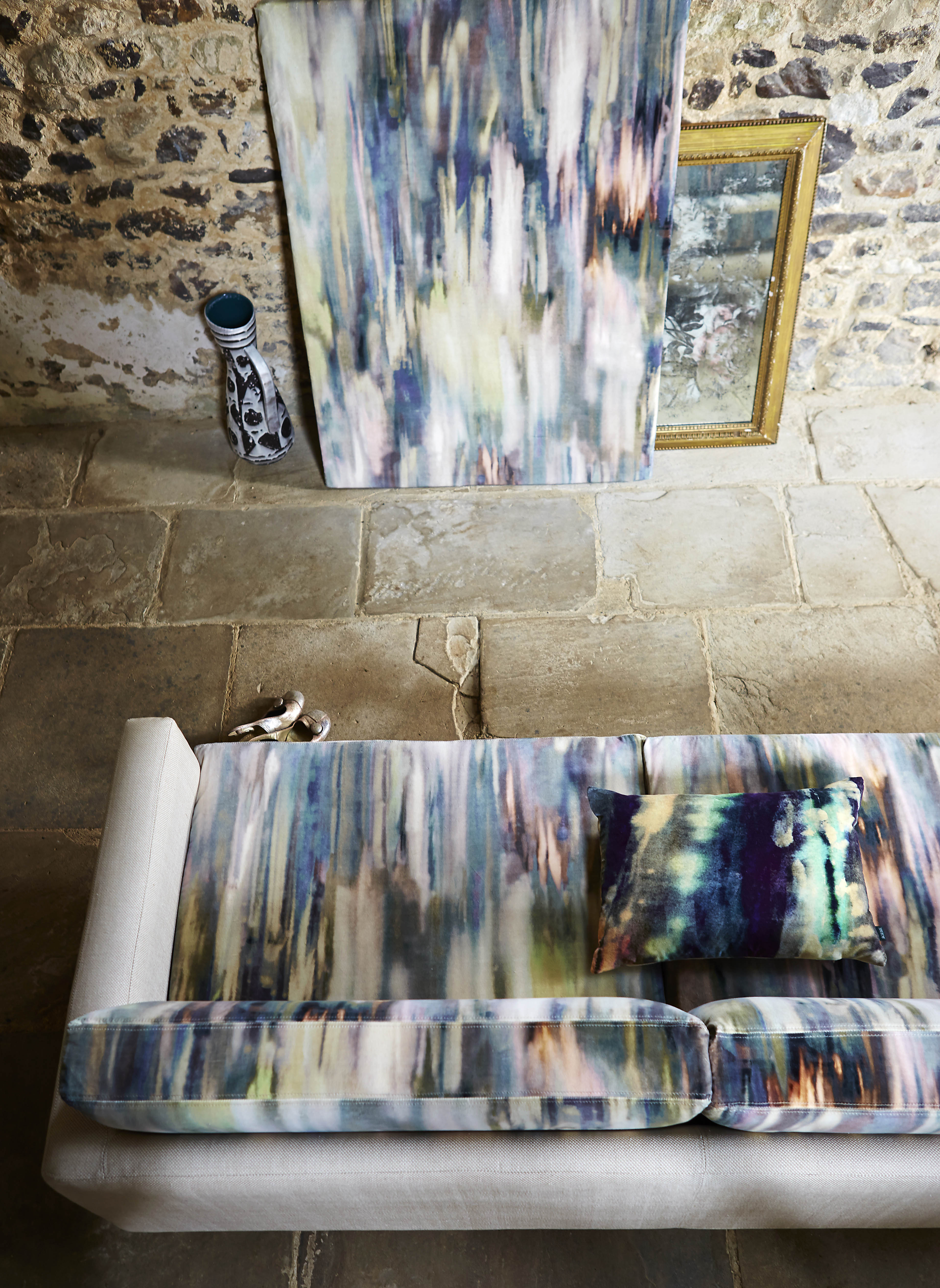 Overhead shot of a living space with a sofa and accent wall both covered in the same abstract painterly print.