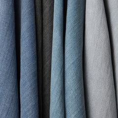 Four woven fabrics draped in a row in shades of navy, blue, charcoal and gray.