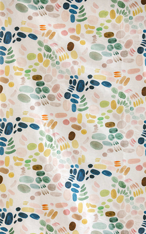 Detail of fabric in a playful paint blotch print in shades of blue, yellow and pink on a cream field.