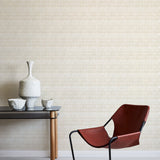 A modernist armchair stands in front of a wall papered in a playful triangular stripe print in white and light brown.