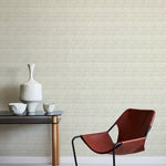 A modernist armchair stands in front of a wall papered in a playful triangular stripe print in gray and cream.