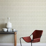 A modernist armchair stands in front of a wall papered in a playful triangular stripe print in gray and cream.