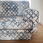 Detail of a sofa upholstered in a diamond checked pattern in shades of cream, gray and blue.