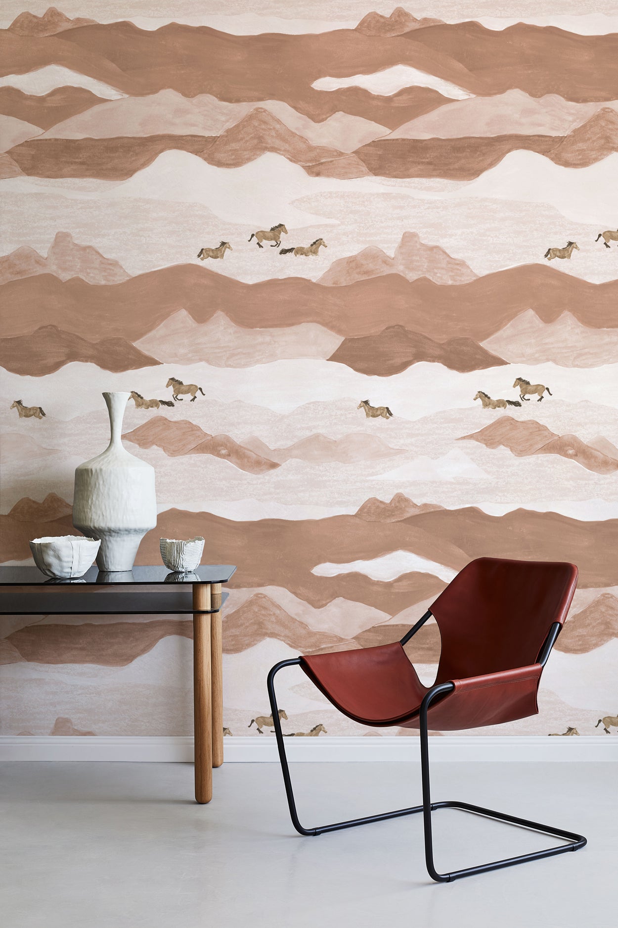 Modern interior with a brown and beige mountain-patterned wall, a red chair, and a small table with decorative items.