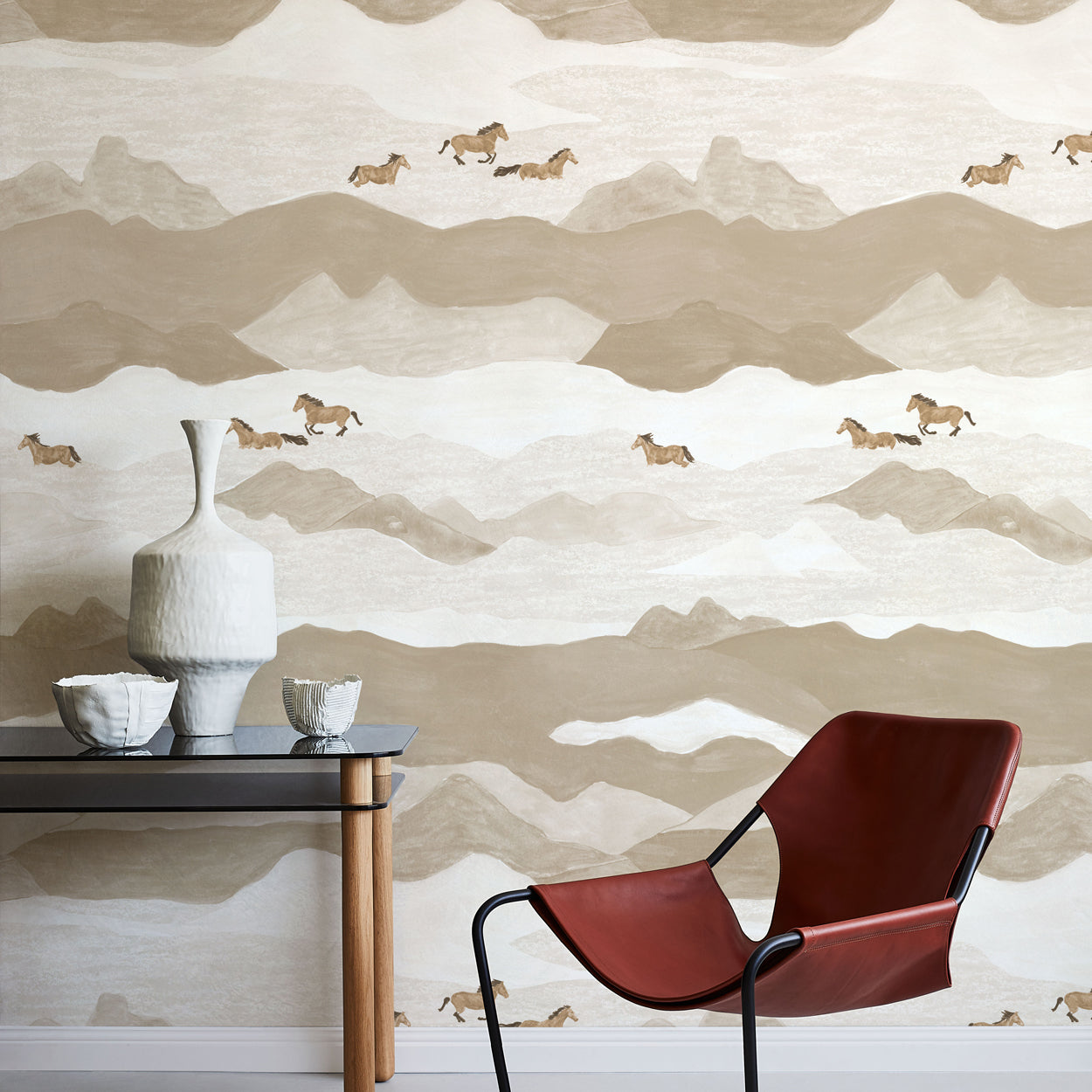 Modern interior with a red chair, table, and decorative items against a mountain-themed wallpaper.
