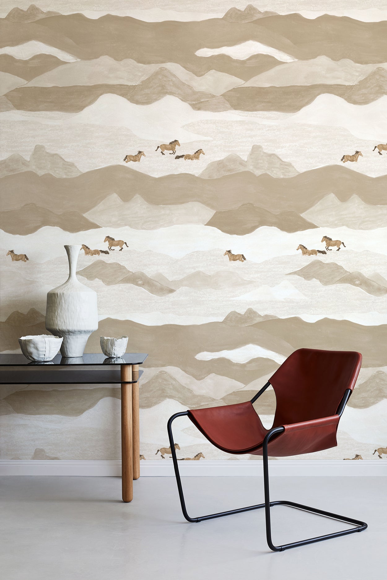 Modern interior with a red chair, table, and decorative items against a mountain-themed wallpaper.