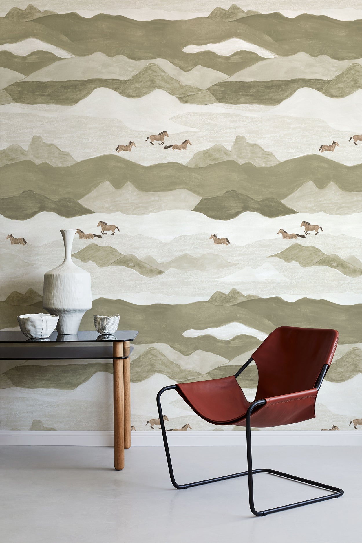 Modern interior with a red chair and table against a mountain and horse wallpaper.