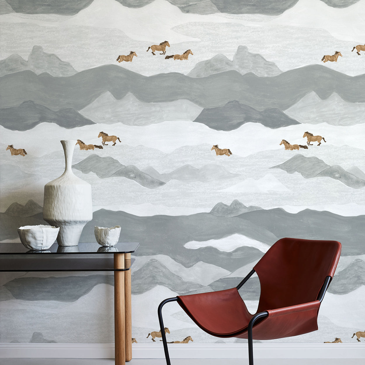 Room interior with a red chair, small table, and decorative items against a mountain-patterned wall.