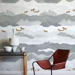 Room interior with a red chair, small table, and decorative items against a mountain-patterned wall.