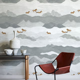 Room interior with a red chair, small table, and decorative items against a mountain-patterned wall.