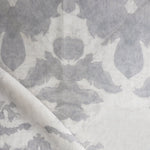 Draped fabric yardage in an abstract ikat print in shades of gray on a greige field.