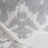 Draped fabric yardage in an abstract ikat print in shades of gray on a greige field.