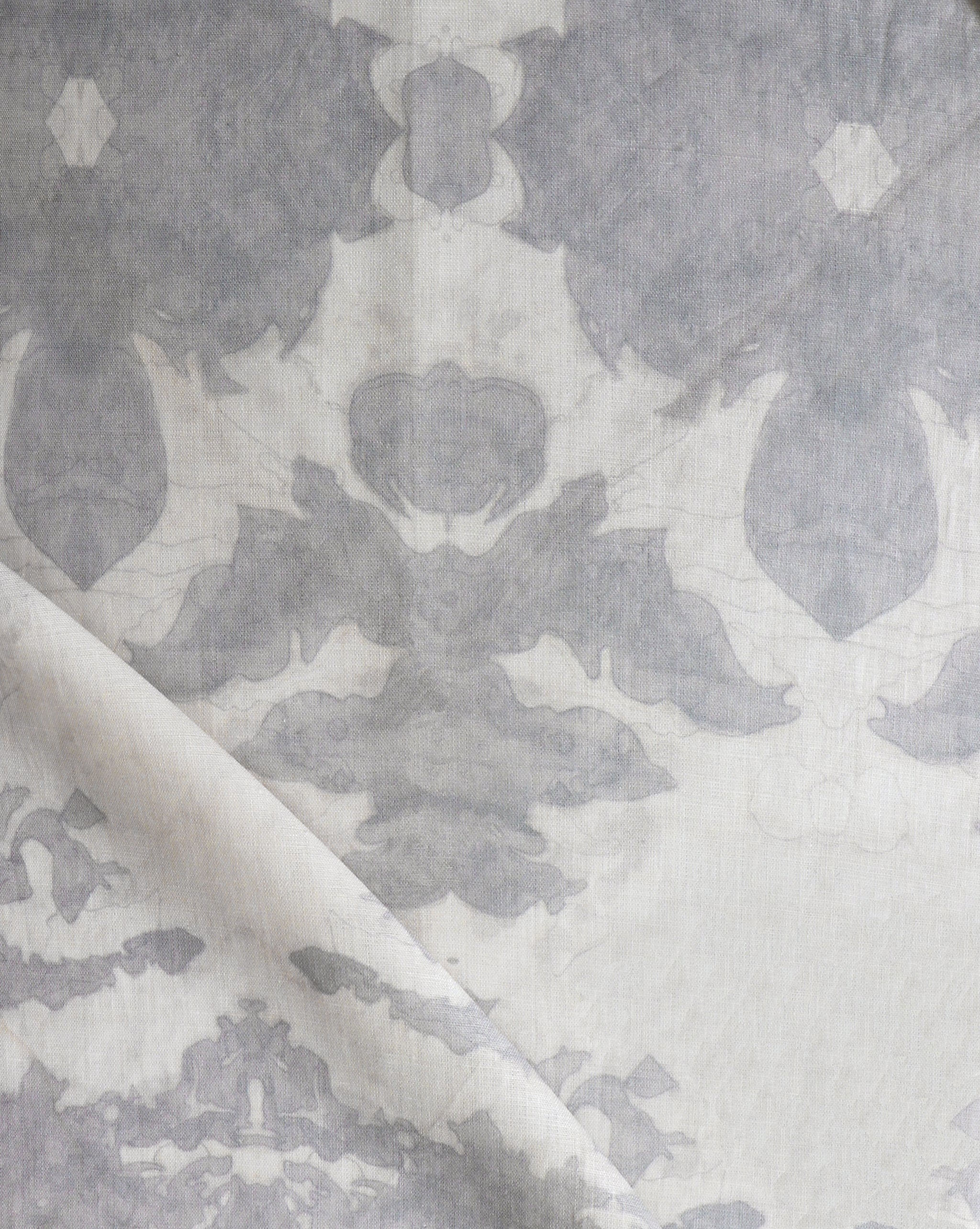 Draped fabric yardage in an abstract ikat print in shades of gray on a greige field.