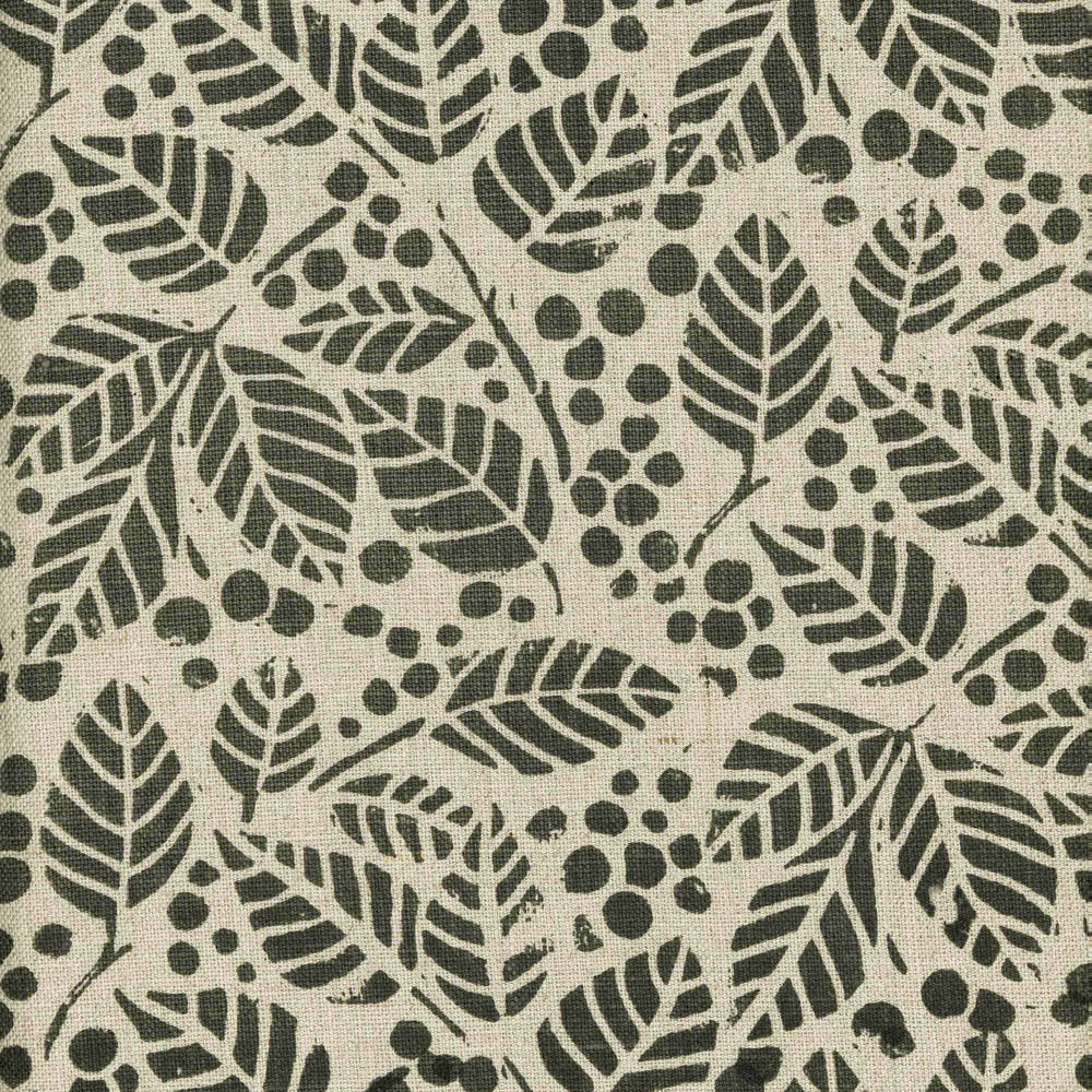 Detail of fabric in a repeating leaf print in dark green on a tan field.