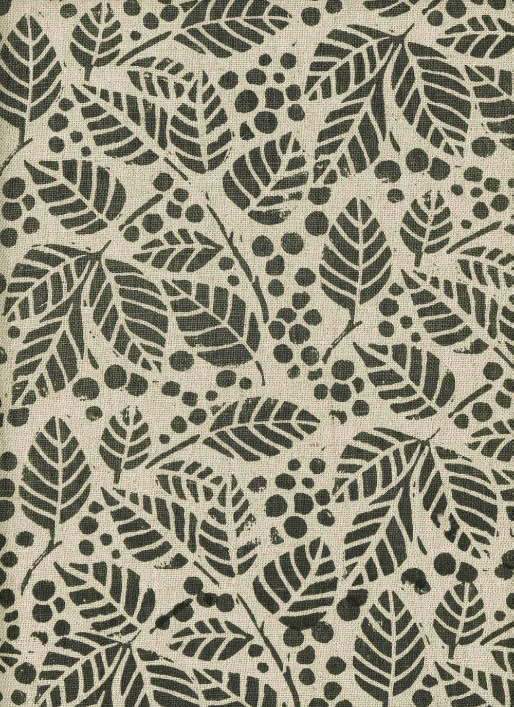 Detail of fabric in a repeating leaf print in dark green on a tan field.