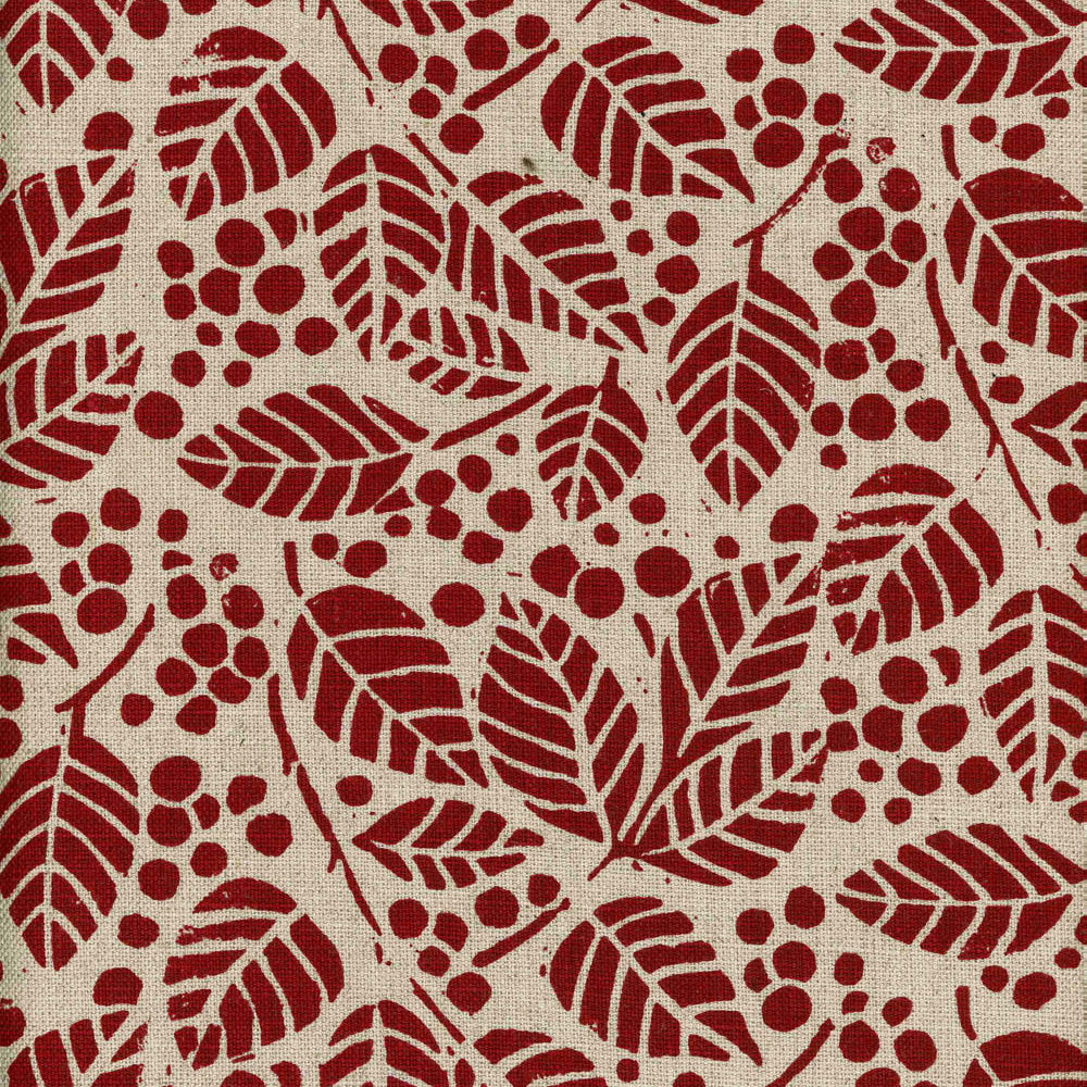 Detail of fabric in a repeating leaf print in red on a tan field.