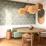 A modernist dining room with a statement wall papered in a painterly palm tree pattern in green, brown and blue-gray.