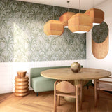 A modernist dining room with a statement wall papered in a painterly palm tree pattern in green, brown and blue-gray.