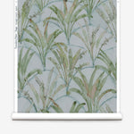 Partially unrolled wallpaper yardage in a painterly palm tree pattern in shades of green and brown on a blue-gray field.