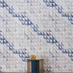 An end table stands in front of a wall papered in a painterly check pattern in shades of blue, gray and white.