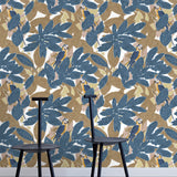 Two minimalist black chairs stand in front of a wall papered in a botanical and parrot print in blue, brown and yellow.