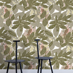 Two minimalist black chairs stand in front of a wall papered in a botanical and parrot print in green, brown and pink.