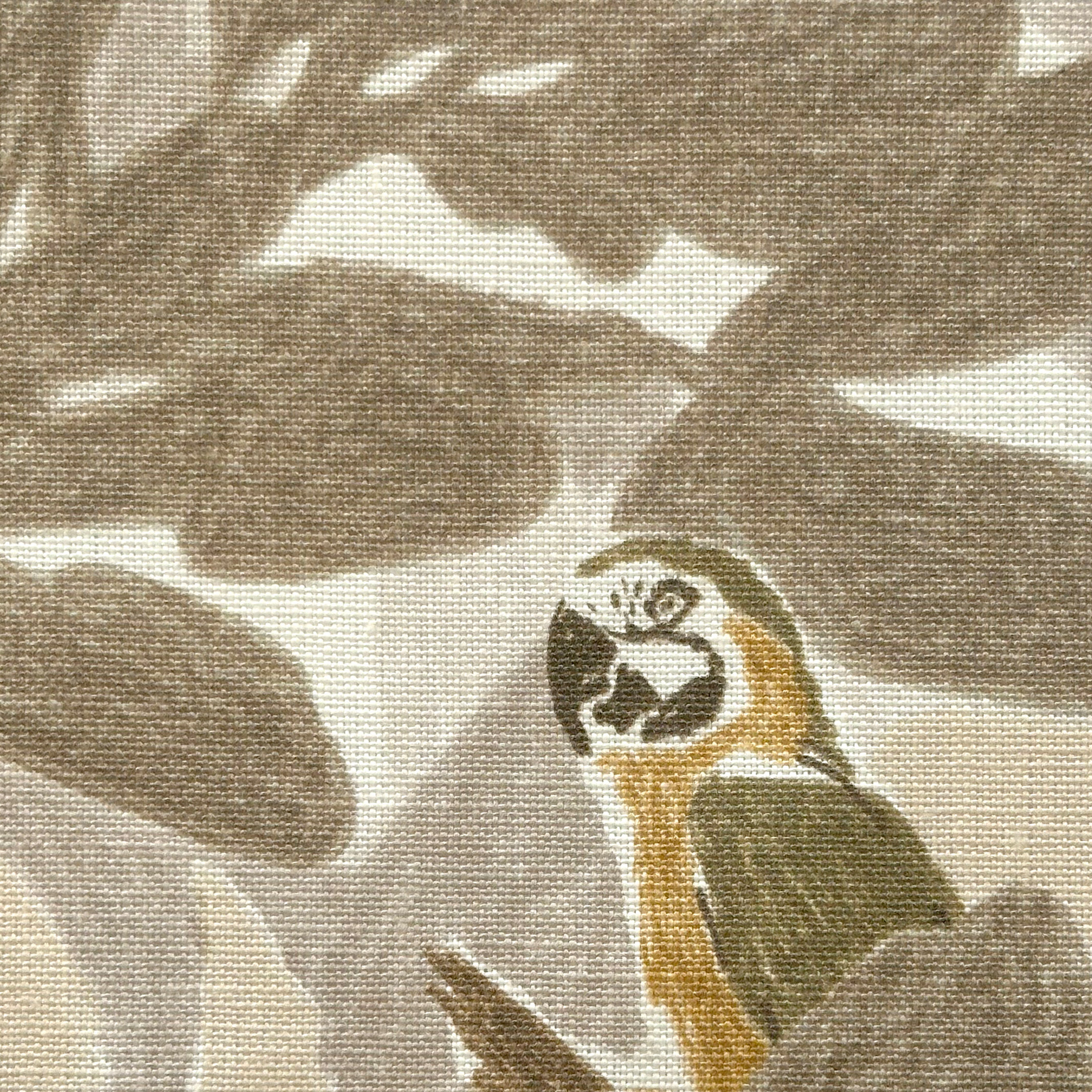 Close-up of fabric in a playful botanical and parrot print in shades of gray, brown and yellow on a white field.