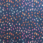 Detail of fabric in a playful paint blotch print in shades of pink, blue and orange on a navy field.