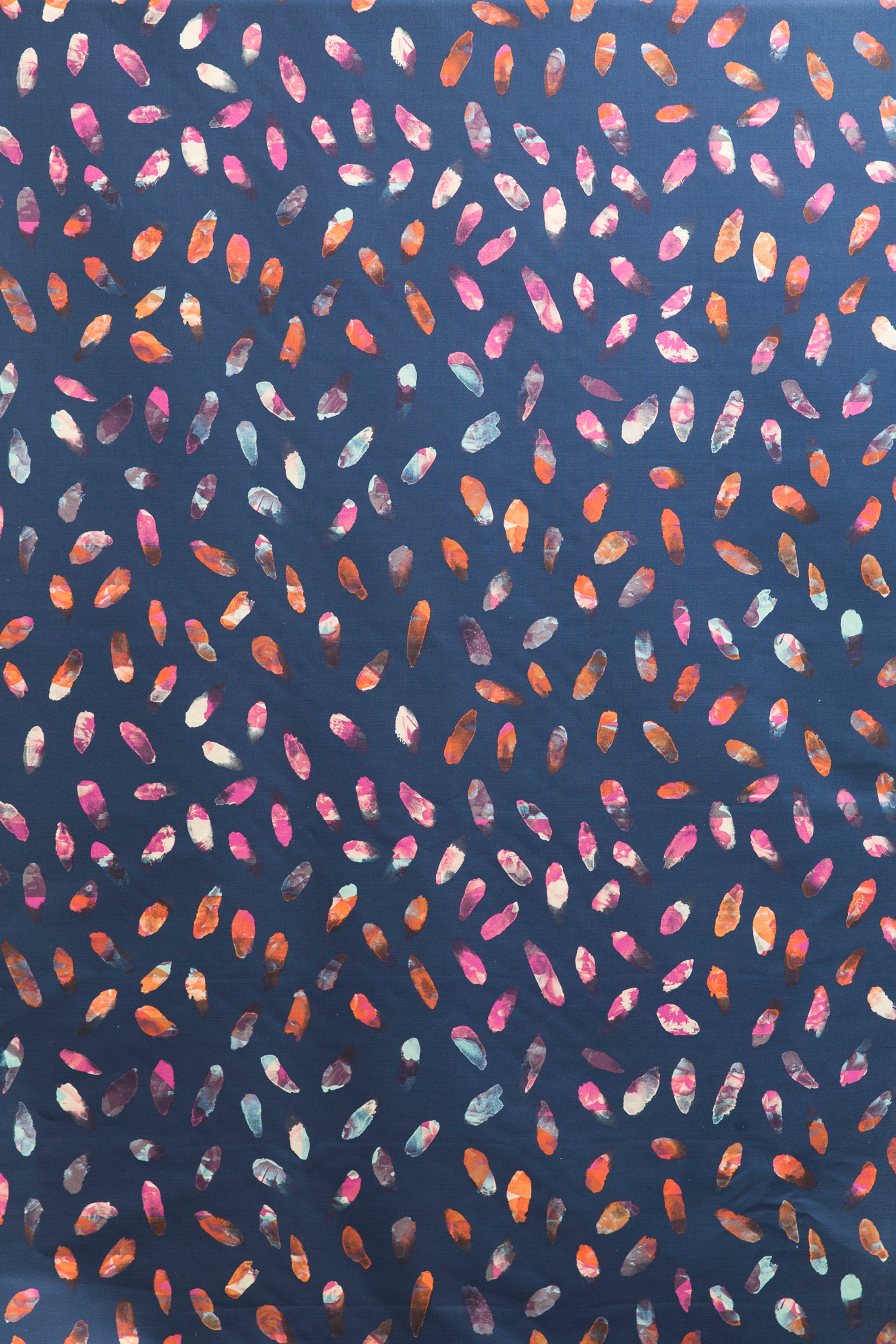 Detail of fabric in a playful paint blotch print in shades of pink, blue and orange on a navy field.