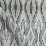 Draped fabric yardage in an abstract diamond print in shades of gray and navy on a cream field.