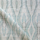 Draped fabric yardage in an abstract diamond print in shades of gray and blue on a cream field.