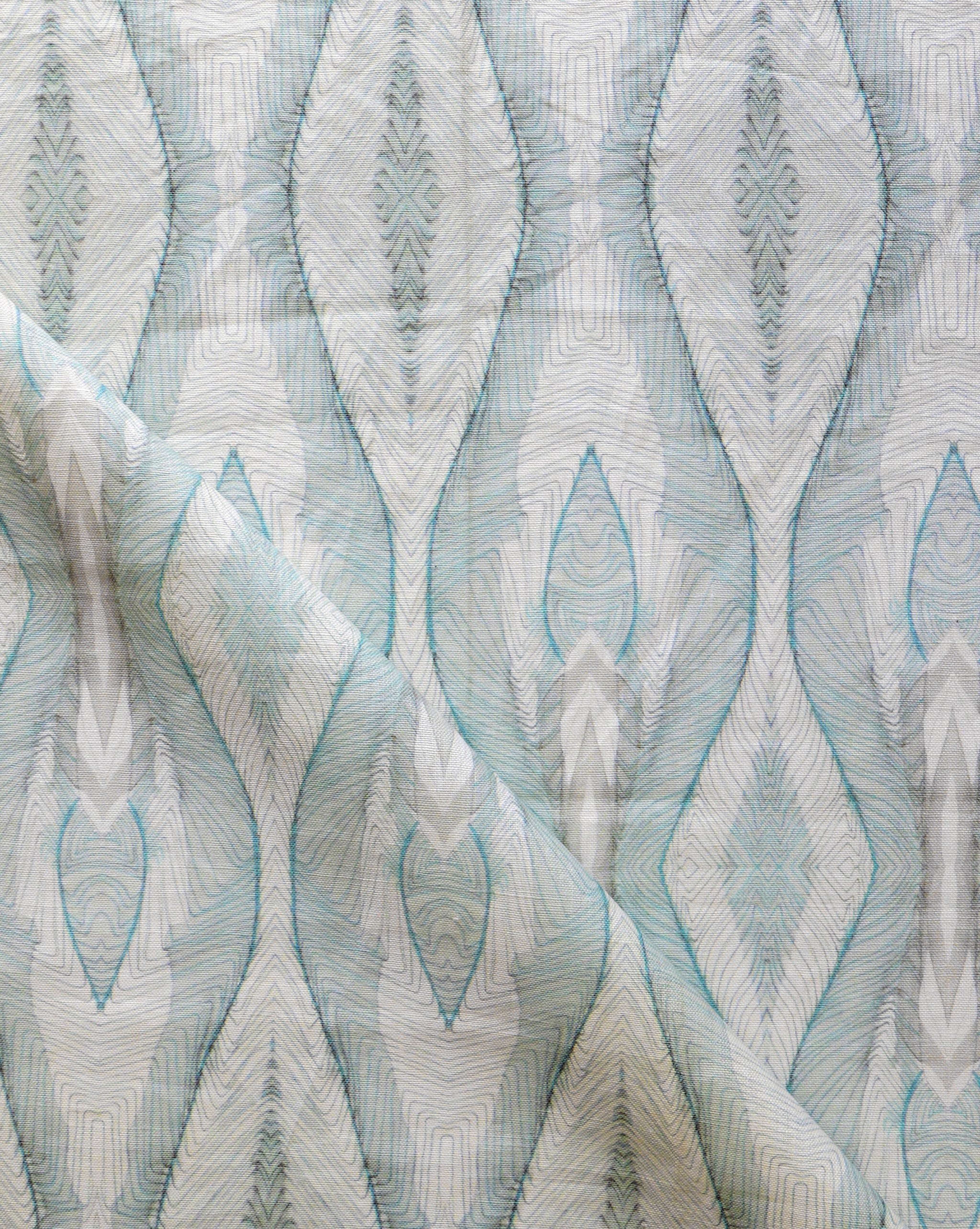 Draped fabric yardage in an abstract diamond print in shades of gray and blue on a cream field.