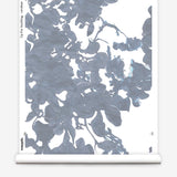 Partially unrolled wallpaper yardage in an abstract floral print in shades of gray and blue on a white field.