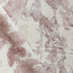 Draped fabric yardage in an abstract botanical print in pink and red on a cream field.