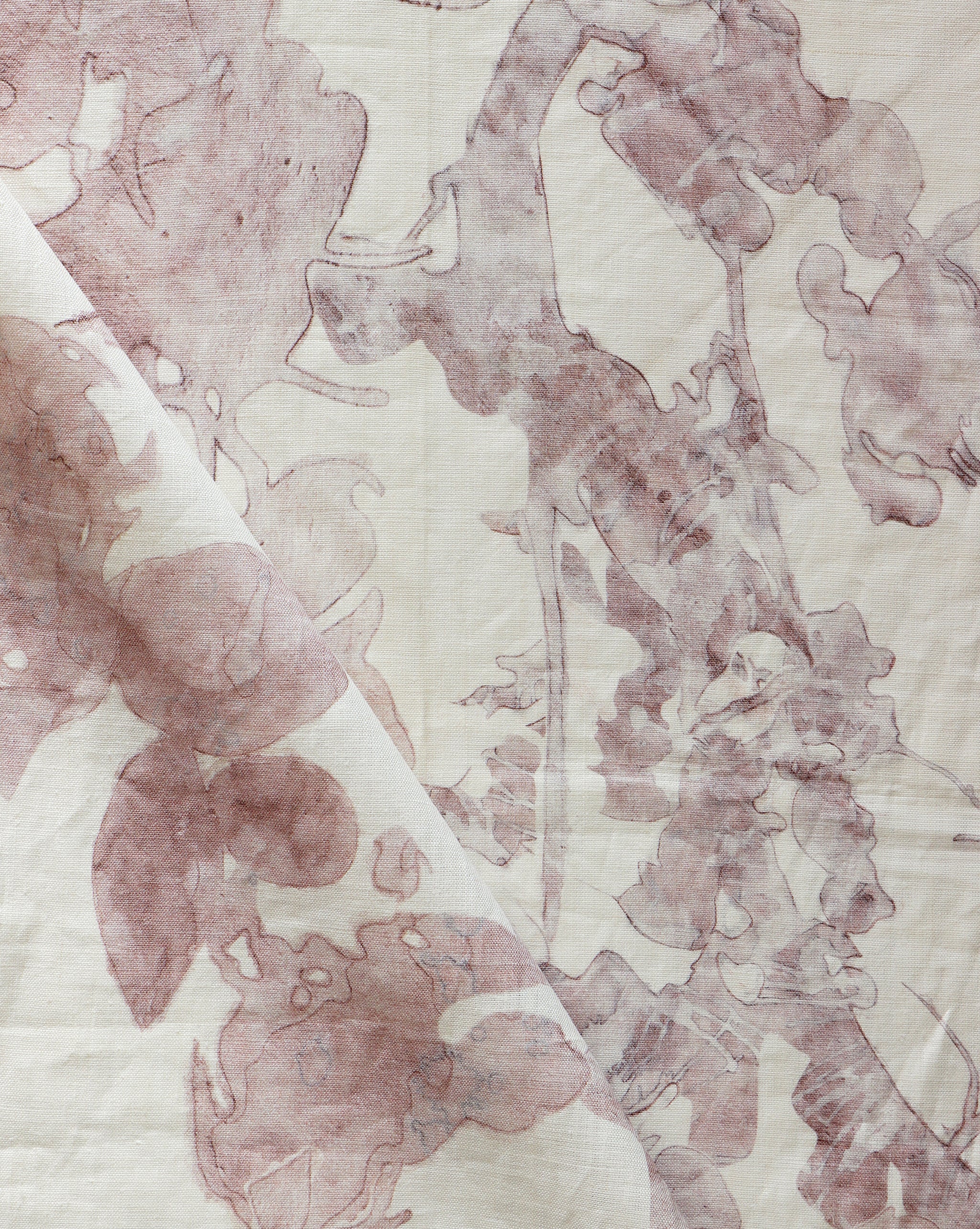 Draped fabric yardage in an abstract botanical print in pink and red on a cream field.